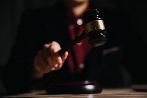 Justice and law concept.Male judge in a courtroom with the gavel, working with, computer and docking keyboard, eyeglasses, on table in morning light photo