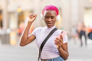 African woman dancing while listening to music with headphones outdoors photo