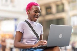 Happy african woman using the laptop on the street photo