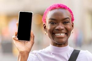 Afro woman with toothy smile showing the screen of mobile photo