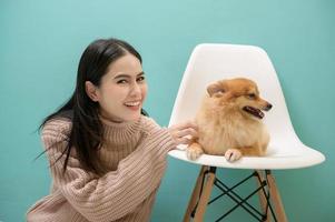 Portrait of Young beautiful woman kisses and hugs her dog over green background. photo