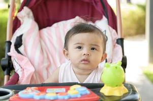 Beautiful mom with a baby girl sitting on baby trolley outdoor in sunshine day photo