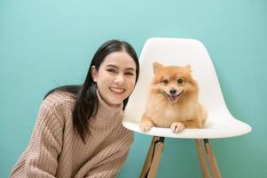 Portrait of Young beautiful woman kisses and hugs her dog over green background. photo