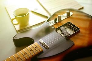eléctrico guitarra y un taza de café en madera antecedentes foto
