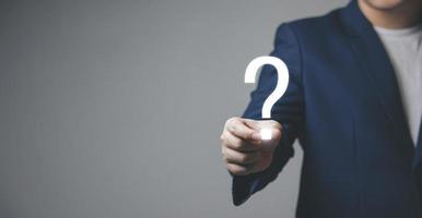 businessman holding question mark. concept of Question mark and FAQs, Ask quiestion online, FAQ concept, what how and why, search information on internet. photo