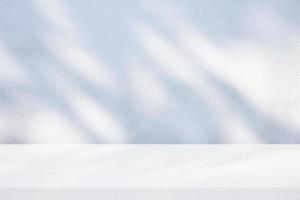 White Table with Fabric Cover with Light and Shadow Leaves on Surface of Concrete Wall Background. photo