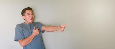 Young man laughing at something and pointing with his hands photo