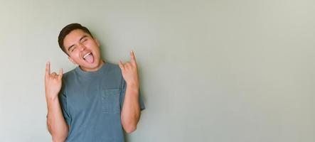 Young man making rock and roll sign and sticking out his tongue photo