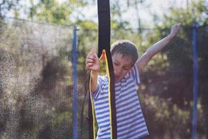 boy jumping on trampoline. child plays and shows thumb up photo