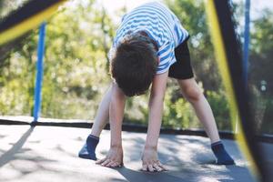 boy jumping on trampoline. the child plays on a trampoline outdoor photo