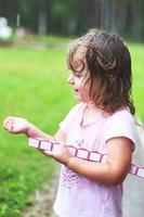 adorable niña caminando con juguete a lluvioso día foto