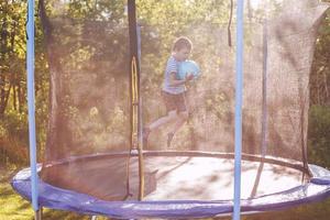 boy jumping on trampoline. child playing with a ball on a trampoline photo