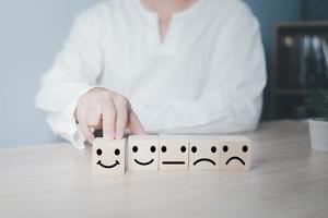 la mano de un hombre de negocios elige una cara sonriente en un círculo de bloques de madera.experiencia de servicio al cliente y encuesta de satisfacción empresarial.calificación muy impresionada.concepto de encuesta de satisfacción. foto