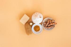 Top view of herbal compress ball with Thai herbal, turmeric, essential oil and bar soap on orange pastel background. Spa background concept. photo