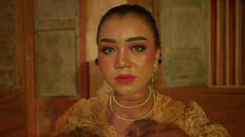 hermosa asiático mujer con maquillaje y un amarillo vestir mirando a el cámara antes de el danza video