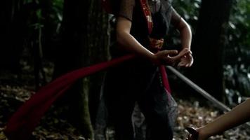 A Couple of a woman dancing together in the woods with a sword and a red cloth video