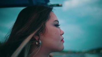 An Asian woman with blonde hair and a sad expression sails the sea on a fishing boat alone while enjoying the sea view video