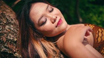 ein asiatisch Frau ist genießen das Atmosphäre von das Insel durch Schlafen auf ein Baum Kofferraum sehr ruhig video