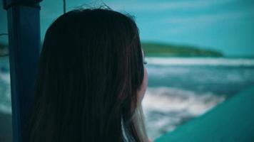 un asiático mujer con rubia pelo y un triste expresión paño el mar en un pescar barco solo mientras disfrutando el mar ver video