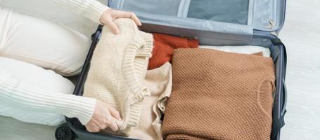 Woman hand packing her winter clothes in luggage. Time to travel, trip, Relax, spring or autumn or winter season and vacation concepts photo