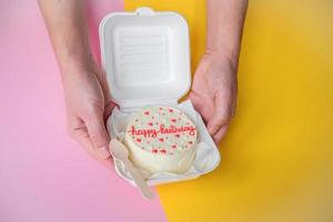 A man's hands hold a festive bento cake with birthday and hearts photo