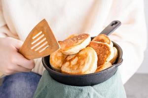 The child holds in his hands a frying pan with pancakes and a spatula for frying. Lifestyle with food photo