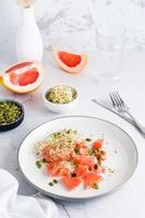 Fresh salad of grapefruit, clover and alfalfa sprouts and pumpkin seeds and cutlery on a plate on the table. Organic vegetarian detox food. Vertical view photo