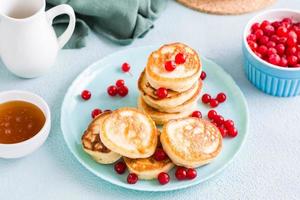 Listo a comer panqueques y arándanos en un plato y un cuenco de miel en el mesa. hecho en casa desayuno postre. foto