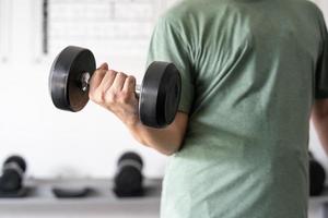 man workout in the indoor gym, man lifting up a Hammer Curl weight exercise. bodybuilding dumbbells in gym. training in fitness gym. photo