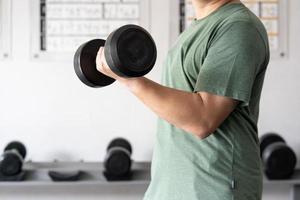 man workout in the indoor gym, man lifting up a Hammer Curl weight exercise. bodybuilding dumbbells in gym. training in fitness gym. photo