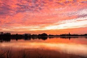 puesta de sol por poco otoño desde el cielo en el horizonte reflejado dentro el agua foto