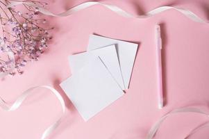 Stickers for writing with a pen on a pink background next to a white ribbon and white flowers photo