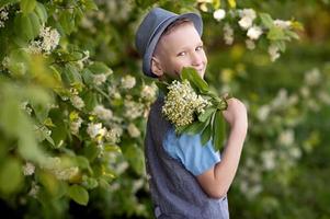 A boy in a blue hat holds a bouquet of lilies of the valley photo