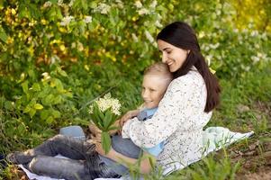 Mom hugs her little son , who is holding a bouquet of lilies of the valley in his hands photo