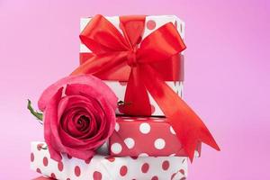 Gift boxes with polka dot on top of each other with bow and pink rose on background. Birthday, February 14, International Women's Day and Mother's Day, March 8, shopping photo