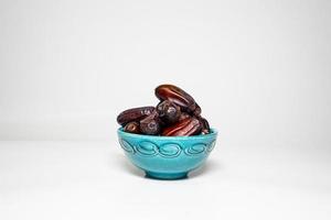 photo a small bowl of dates next to a handful on white background. high quality photo