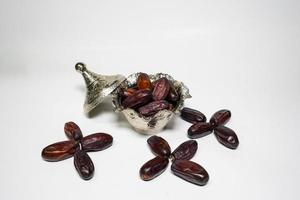 photo a small bowl of dates next to a handful on white background. high quality photo