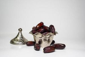 photo a small bowl of dates next to a handful on white background. high quality photo