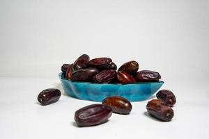 photo a small bowl of dates next to a handful on white background. high quality photo