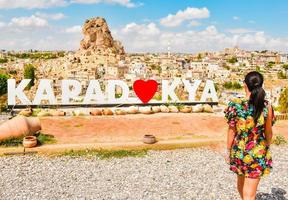 Caucasian female tourist capture with smart phone Ortahisar castle landscape in Cappadocia while summer solo travels in sunny day ,Turkey tourism concept photo