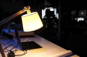 Working overtime - laptop in a dark room illuminated by a table lamp photo