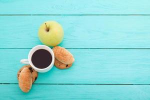 Cup of coffee with croissants and cookies and red roses on blue wooden background. Copy space. Mock up. Top view. Valentine mother day. photo