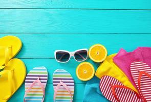 Colorful flip flops, sunglasses and oranges on blue wooden background. Top view and copy space. Summertime photo