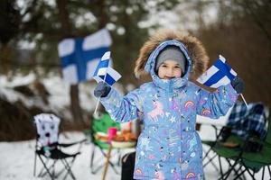 finlandés pequeño niña con Finlandia banderas en un bonito invierno día. nórdico escandinavo gente. foto