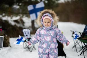 finlandés bebé niña con Finlandia banderas en un bonito invierno día. nórdico escandinavo gente. foto