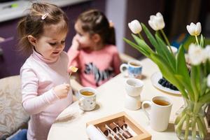 Children eat fruits and desserts, drink tea at home in the evening kitchen. photo