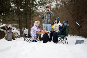 Family with three children in winter forest spending time together on a picnic. photo