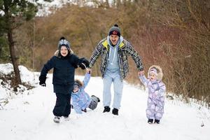 Father with three kids holding hands and walking in winter forest. photo