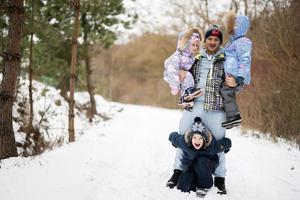 Daughters on a hands of dad in winter forest. photo