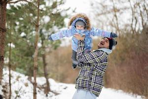 Daughter on a piggy back ride with her dad in winter forest. photo